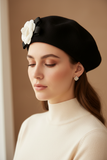 Model wearing a black and white camelia flower wool felt French beret hat